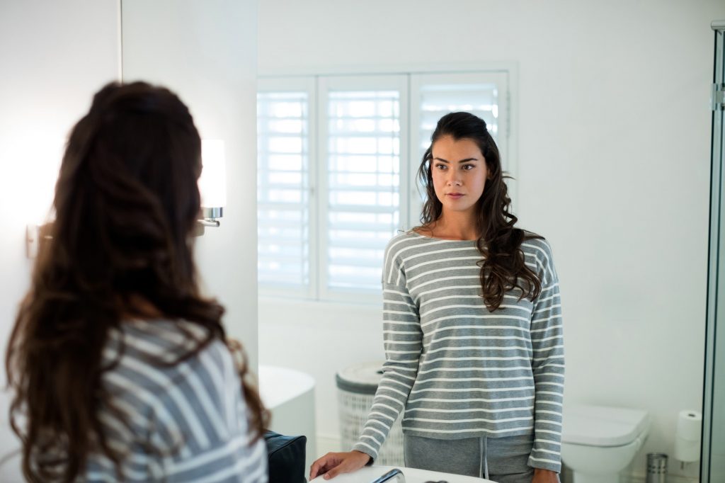 Woman looking at herself in the bathroom mirror